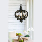Black ornate pendant light with wood accents and chain suspension above styled table - Elirian