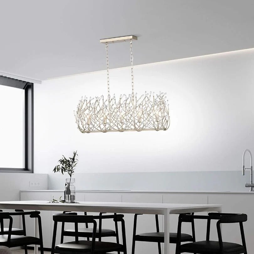 Modern crystal chandelier with vintage silver finish hanging above white kitchen island with black chairs - Elirian