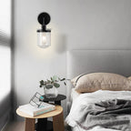 Modern black wall sconce with clear glass shade illuminating minimalist bedroom - Elirian