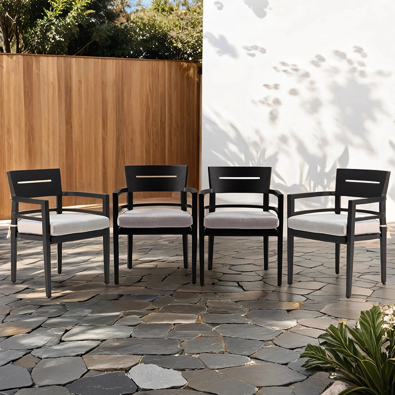 Four black aluminum outdoor dining chairs with gray cushions arranged on slate patio - Elirian